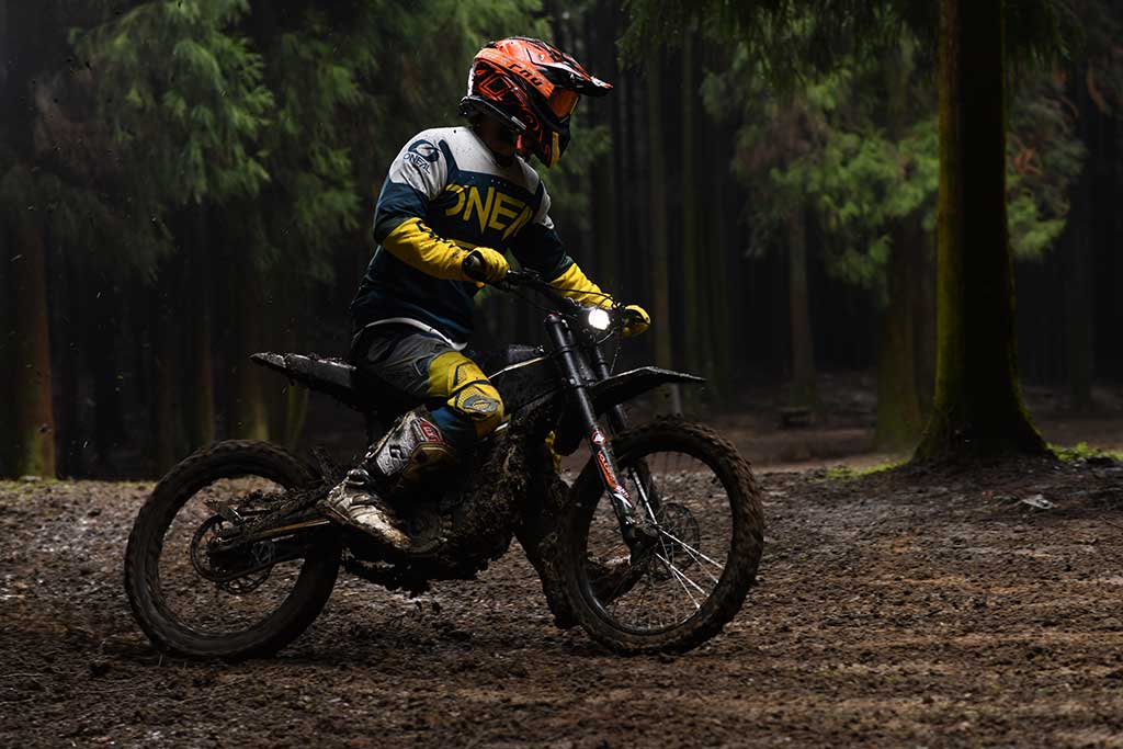 Sähköcrossilla ajava kuljettaja metsässä – Talaria sähkömopo offroad-ajossa.